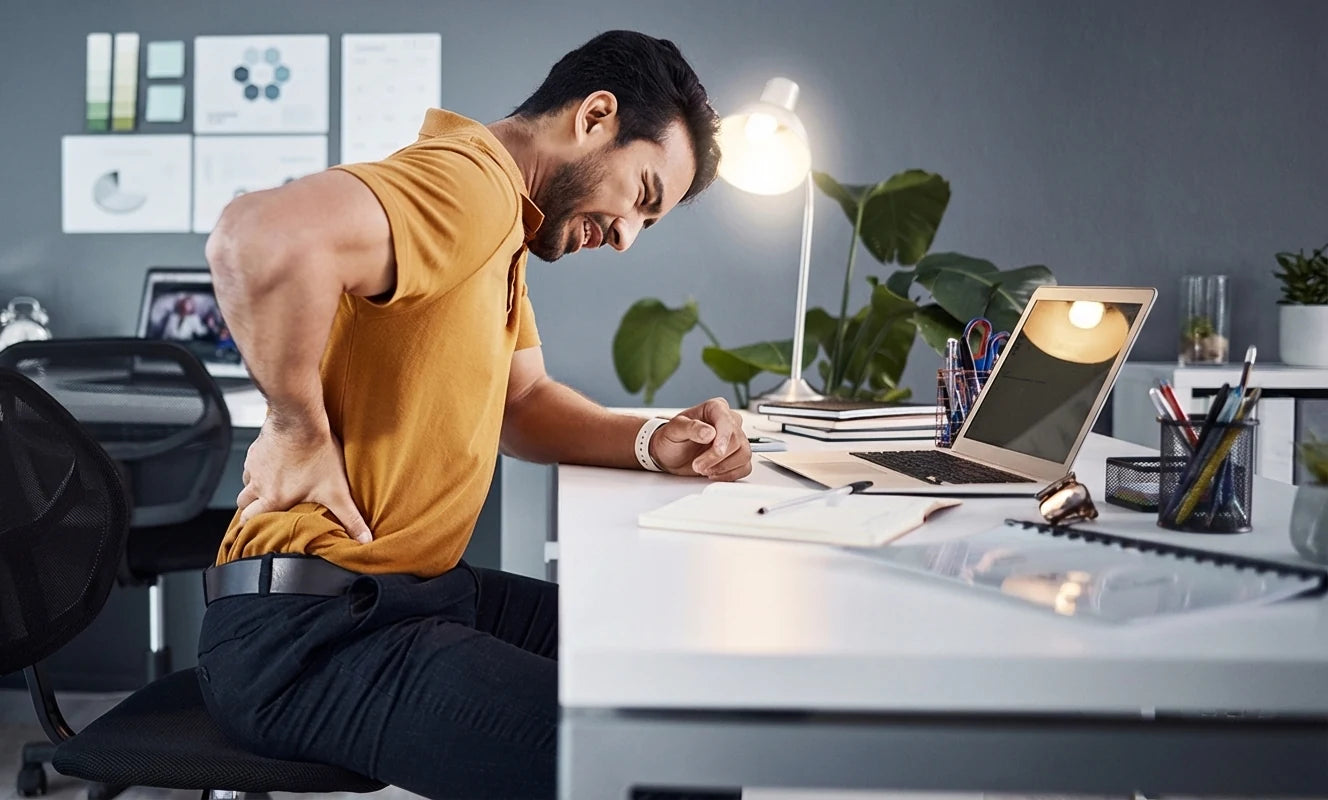 Man experiencing back pain at his desk, highlighting the need for Sunaofe ergonomic office solutions.