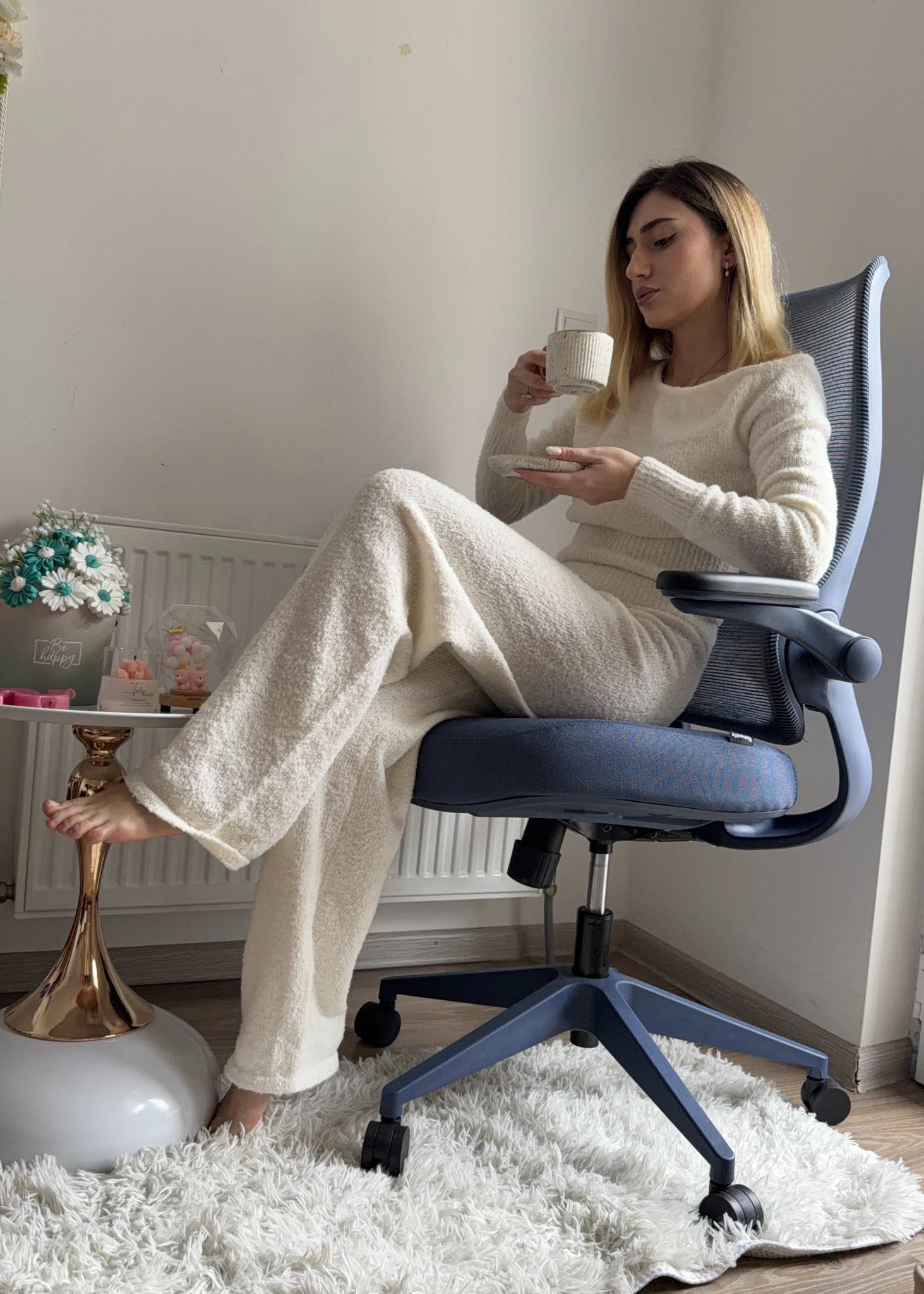 A woman enjoying a coffee break in a Sunaofe ergonomic mesh office chair for home office comfort.