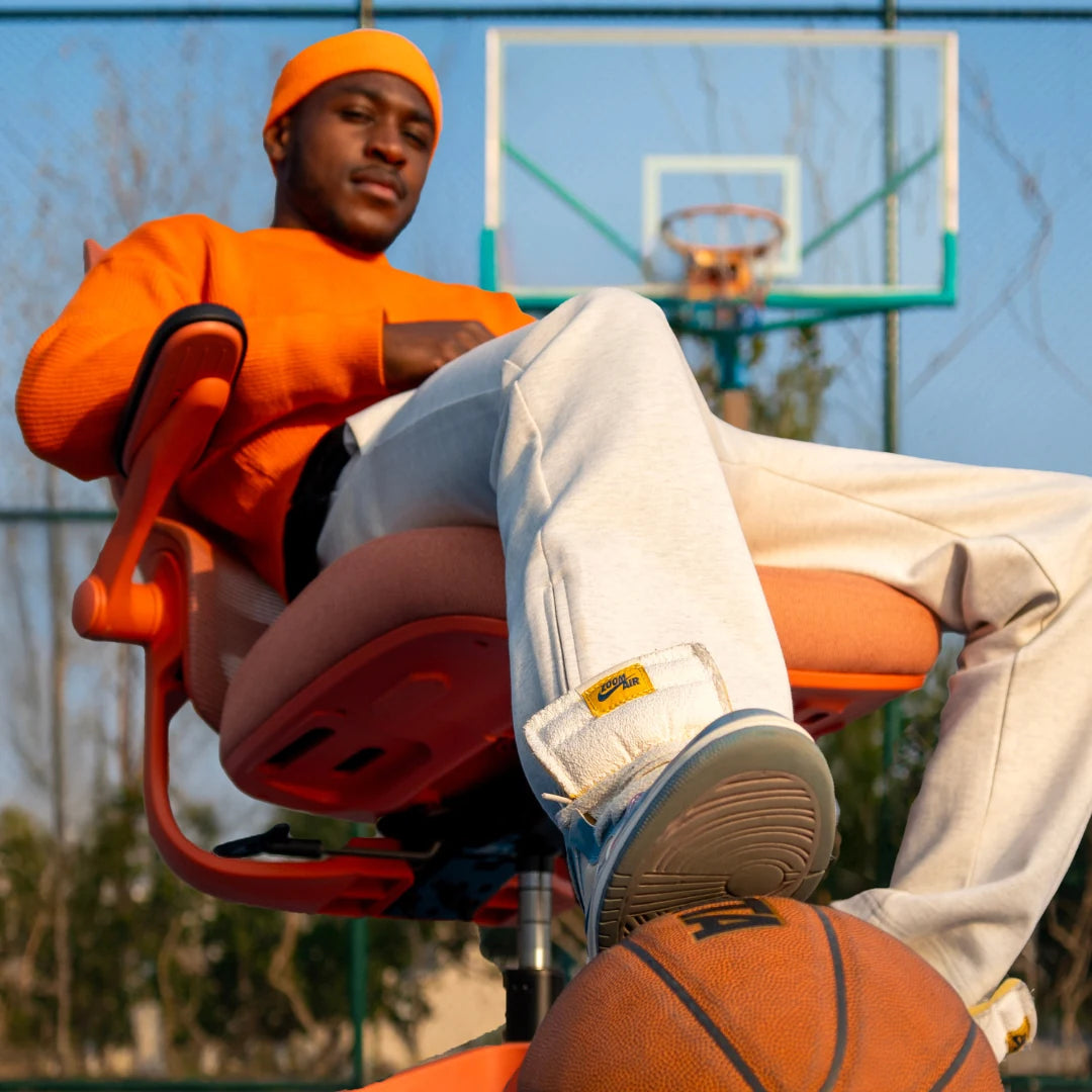 A Sunaofe ergonomic chair on a basketball court with a stylish man relaxing.