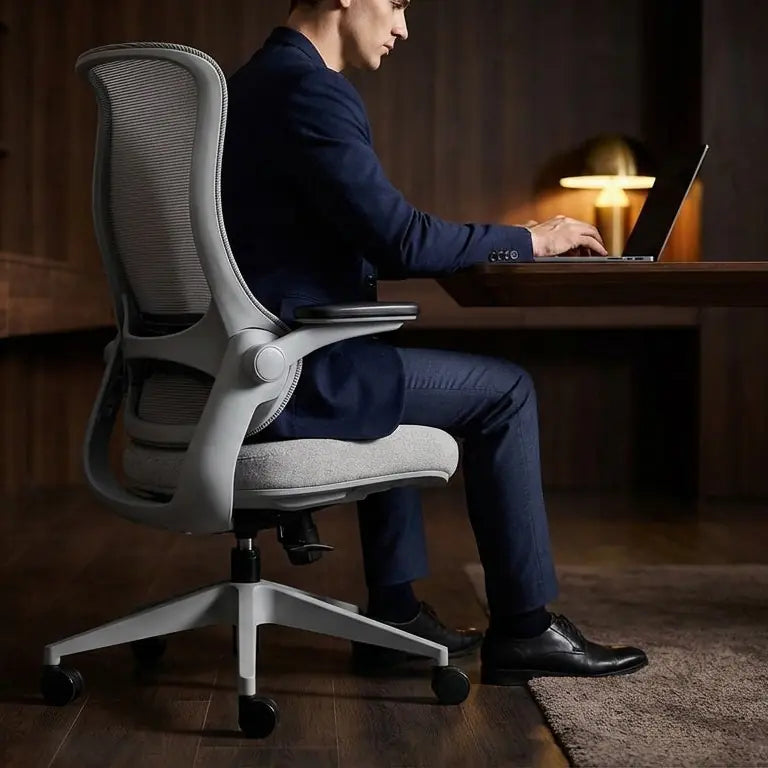 A person sits in the Sunaofe ergonomic office chair while working on a laptop at a desk.