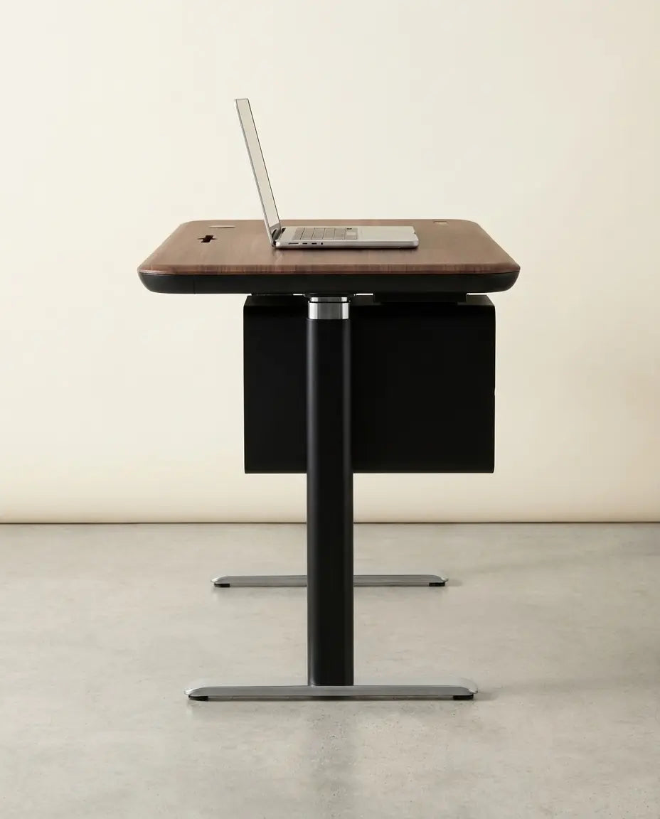 Sunaofe height adjustable desk with a walnut top and laptop in a studio setting.