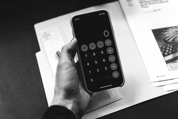 A person using a smartphone calculator at a Sunaofe workspace to manage office finances and productivity.