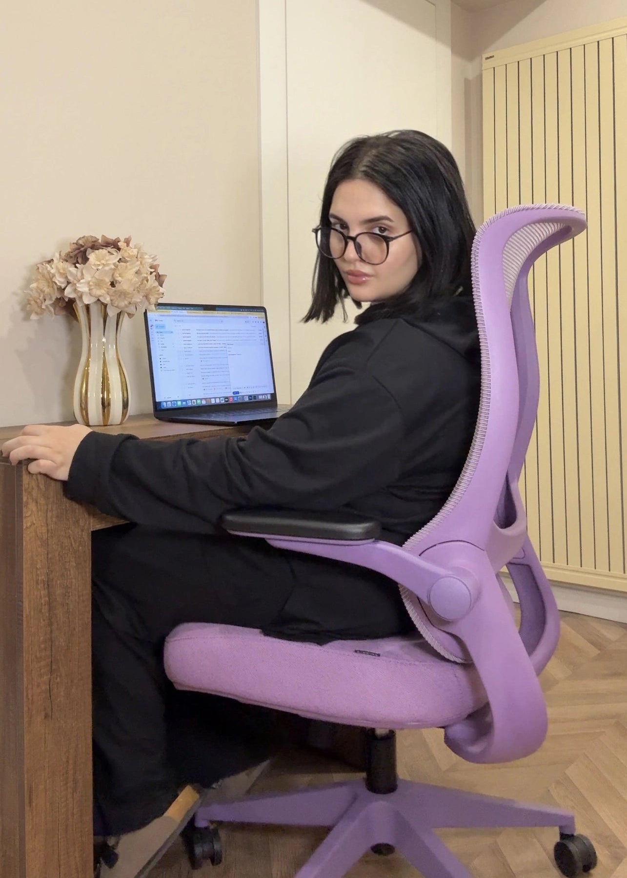 A woman working at a desk sitting in a vibrant purple Sunaofe ergonomic office chair for better workspace wellbeing.