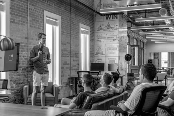A team gathering in a modern Sunaofe workspace with industrial design elements and ergonomic office seating.