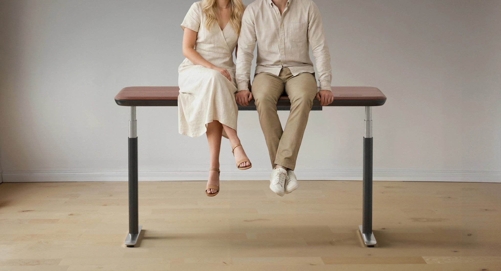 A couple sits on a sturdy Sunaofe height-adjustable standing desk, demonstrating its durability and weight capacity.