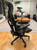 A Sunaofe ergonomic mesh office chair with adjustable armrests in a modern home living room setting.