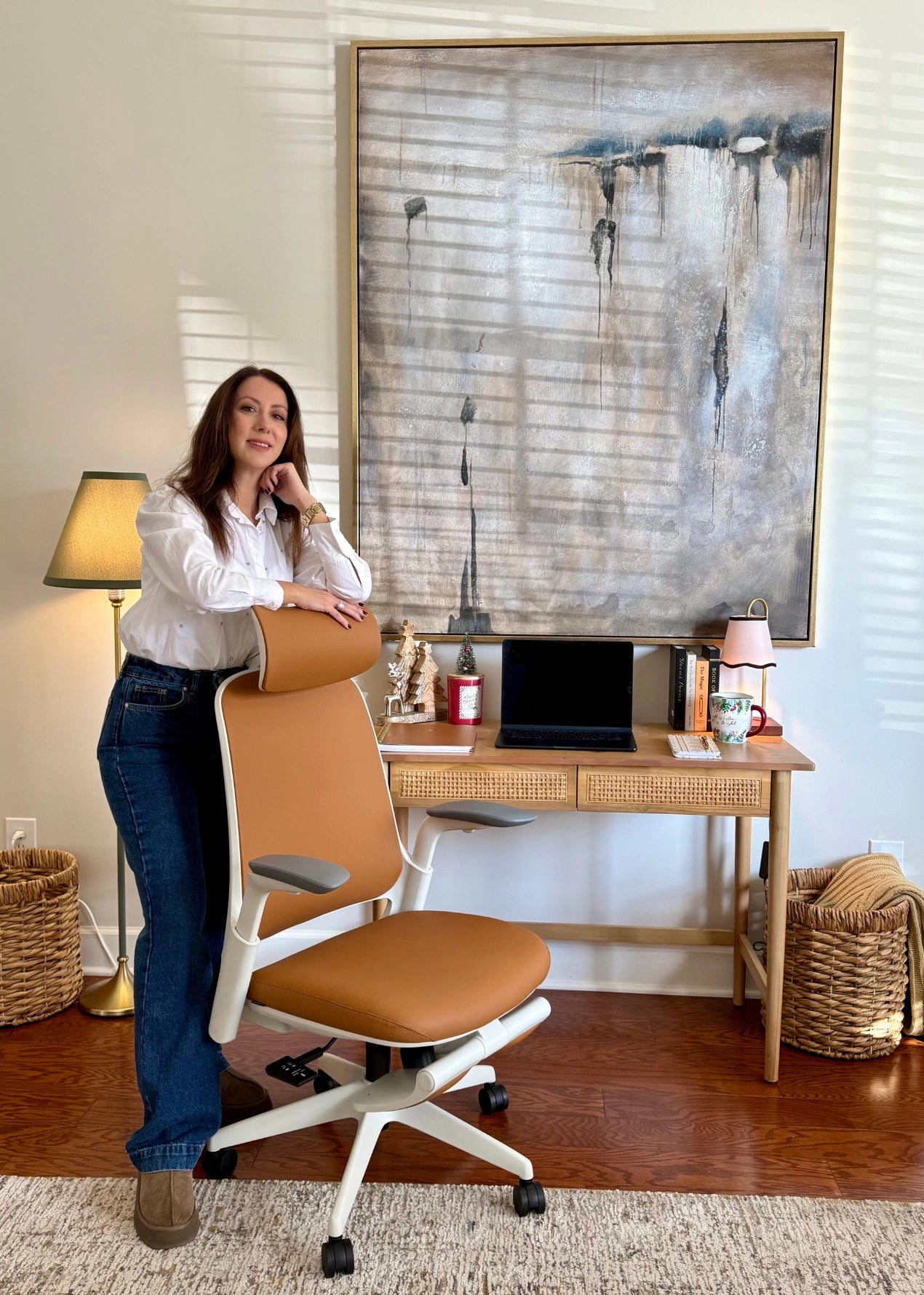 A woman posing with a Sunaofe ergonomic tan office chair in a beautifully decorated home office workspace.