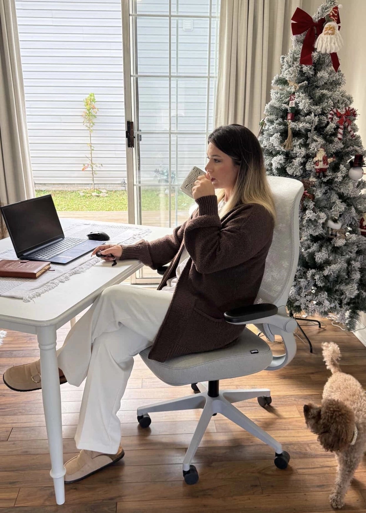 A woman sits in a white Sunaofe ergonomic office chair in a festive home office with a Christmas tree.
