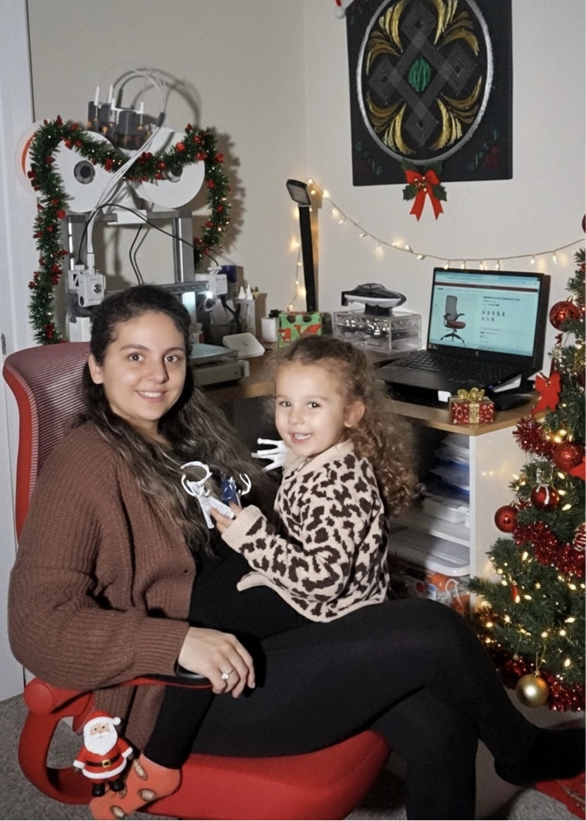 A woman and child sitting in a red Sunaofe ergonomic office chair in a decorated home office for Christmas.