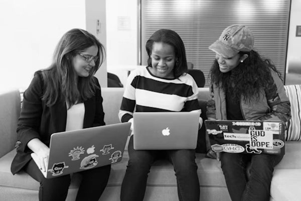 Three women collaborating on laptops in a modern Sunaofe workspace environment to foster creativity and productivity.